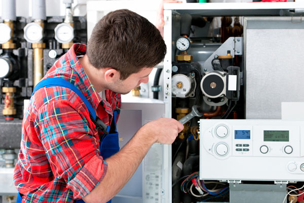 HVAC technician inspecting and repairing boiler controls in Drexel Heights